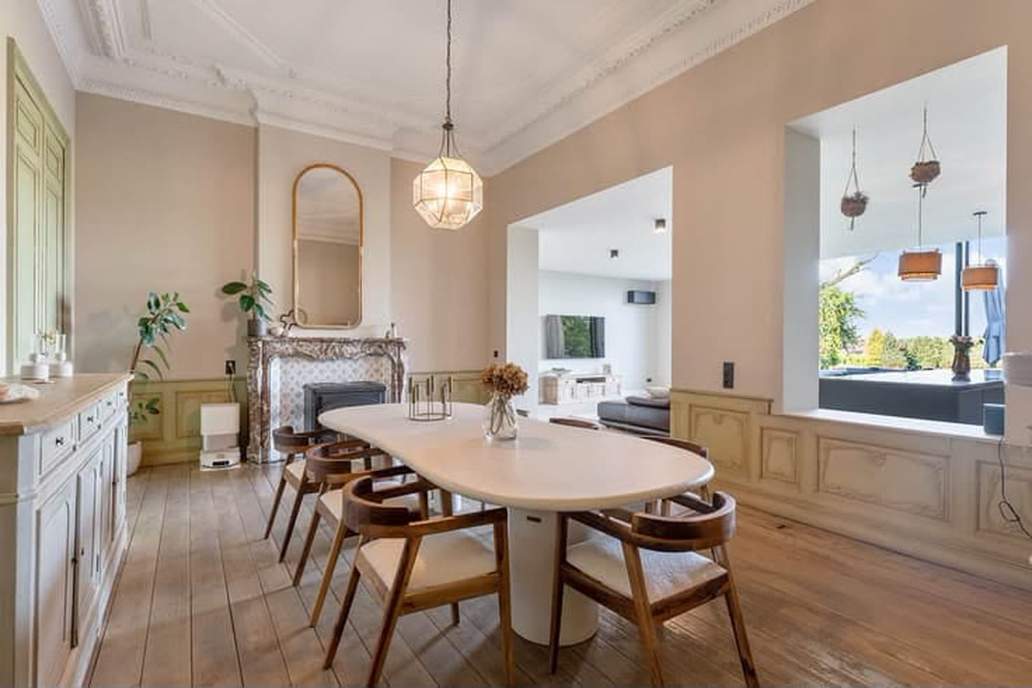 Eetkamer in het oude gedeelte met marmeren schouw, ovale tafel en hoge plafonds met sierlijst.